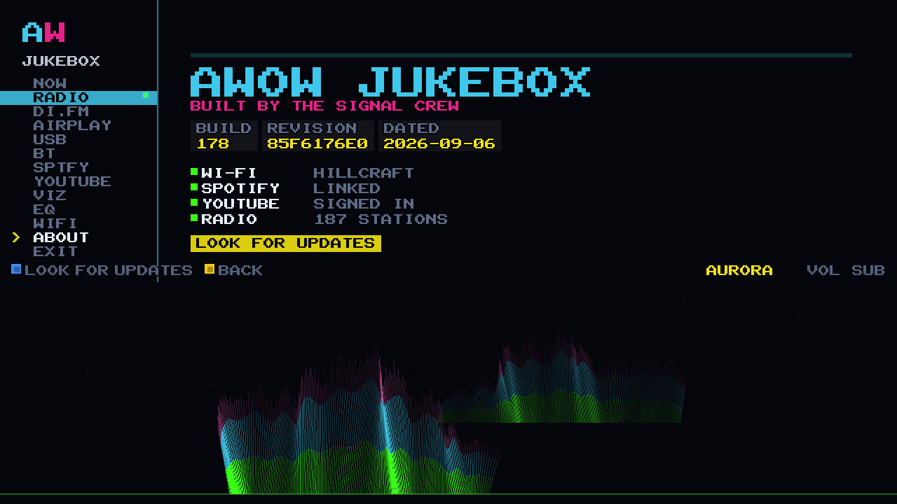 The ABOUT screen on the cabinet: AWOW JUKEBOX, BUILT BY THE SIGNAL CREW, the build plates, four green ticks and LOOK FOR UPDATES