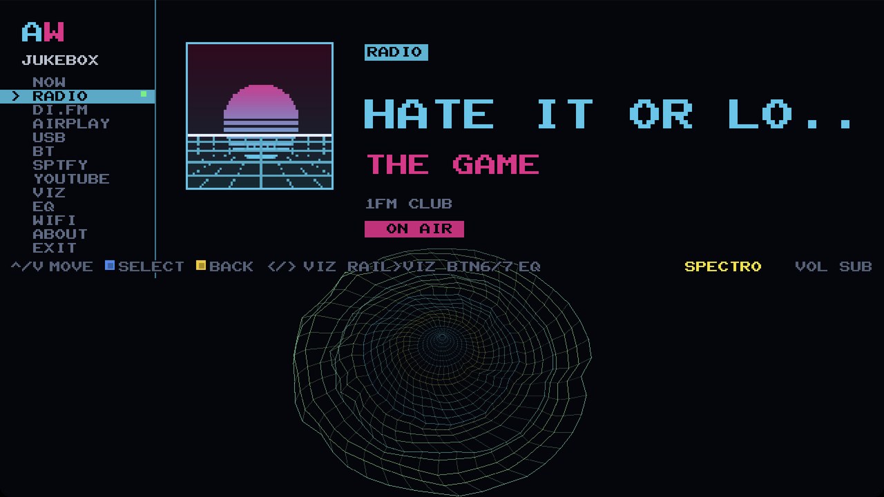 The NOW screen on the cabinet: a house station on air, the track title in big cyan pixel type, the sleeve in the panel and the SPECTRO visualizer running underneath